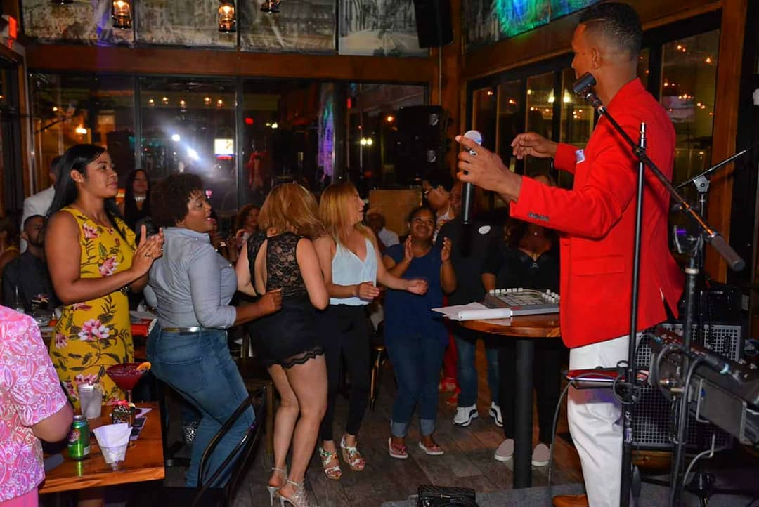 Charlie Pe cantando en vivo con chaqueta roja frente al público en un club (2018)