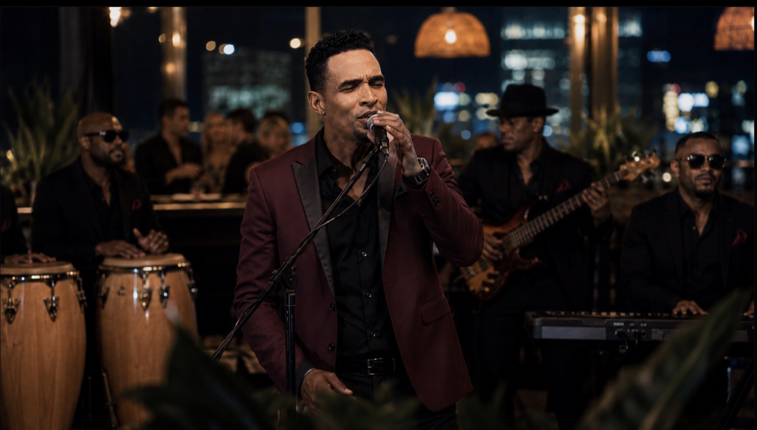 Primer plano de Charlie Pe cantando al micrófono en el escenario de un lounge en una azotea de noche, con el horizonte de la ciudad de fondo, vestido con blazer color vino